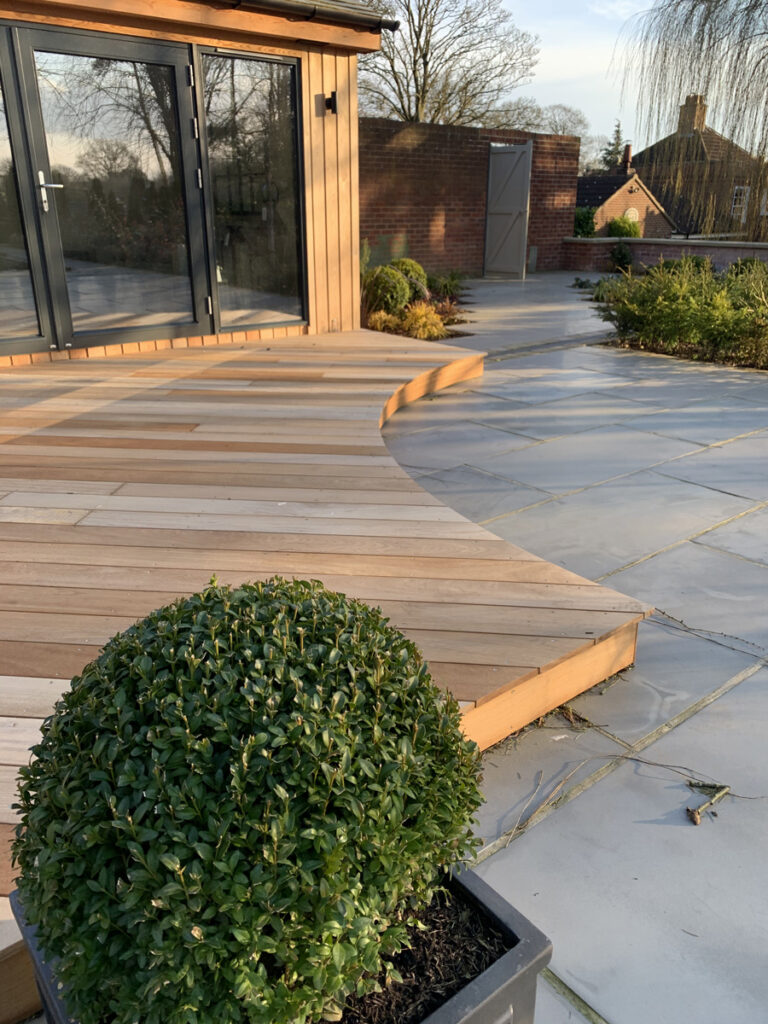 Curved wooden decking and flagstone patio