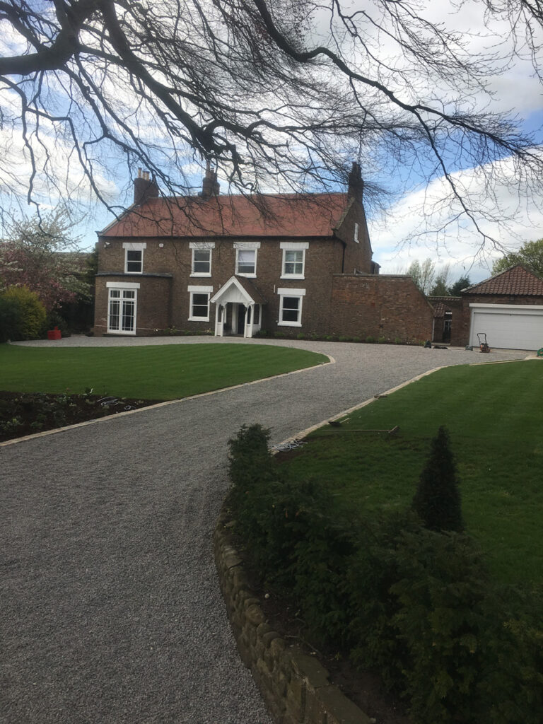 Newly laid gravel drive between two well maintained lawns
