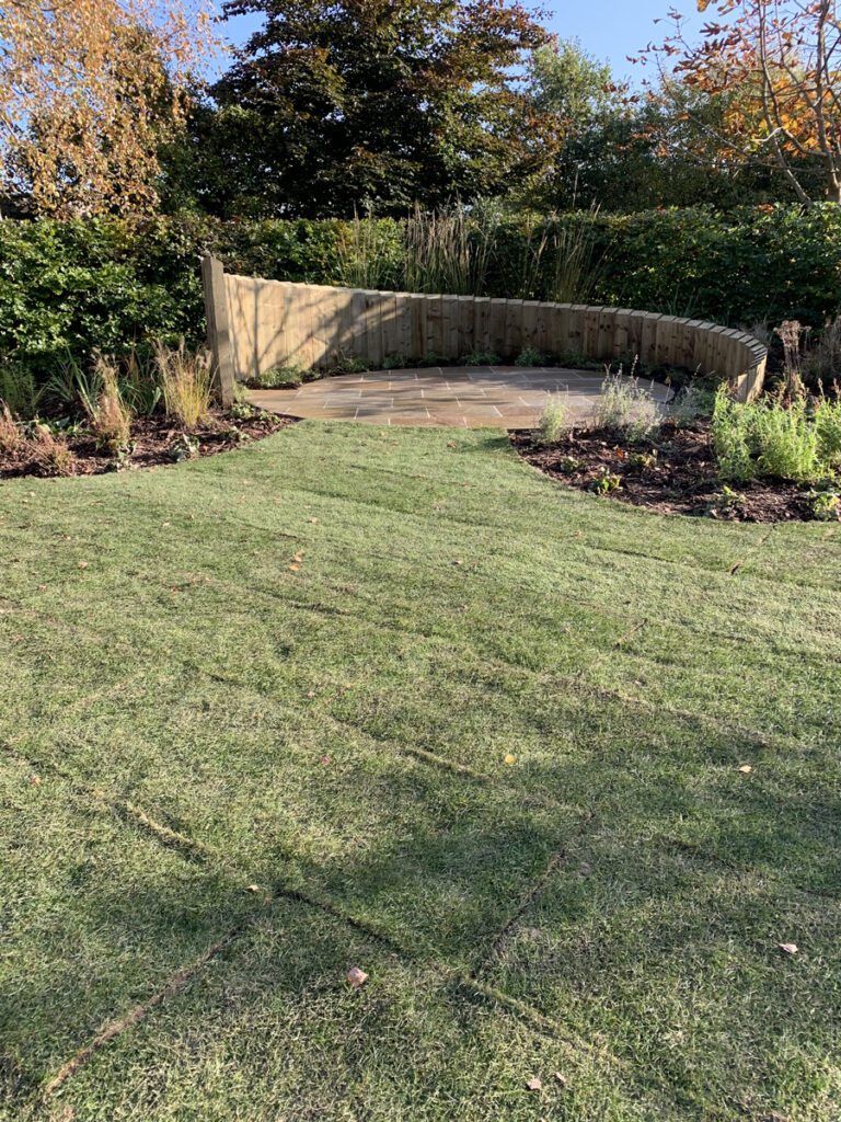 Newly laid lawn leading to circular feature patio