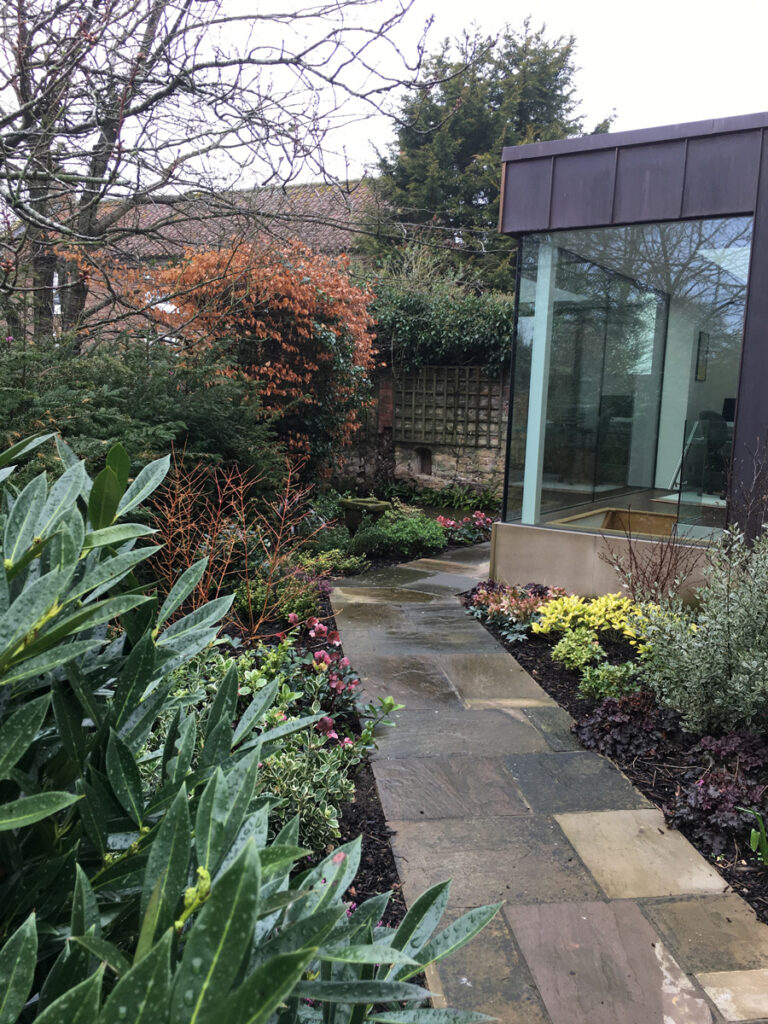 Stone paved path leading between newly planted garden beds